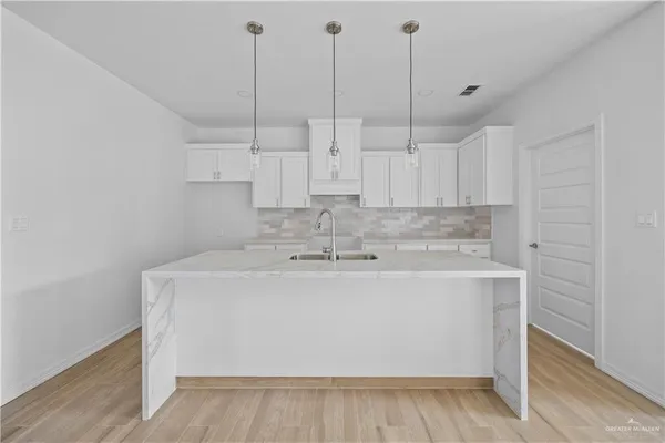 a view of a kitchen with a sink dishwasher a kitchen island a stove with wooden floors