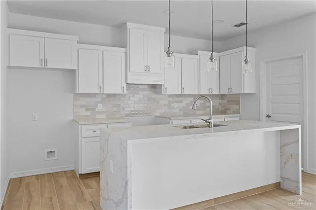 a view of a kitchen with kitchen island a sink wooden floor and view living room