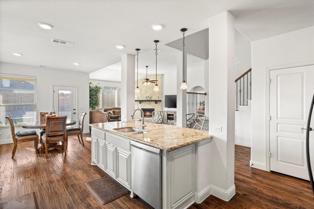 1814 Chadwick Lane Forney, TX 75126 - Photo 40 of 40 Kitchen featuring dark wood finished floors, dishwasher, light stone countertops, a fireplace, and open floor plan