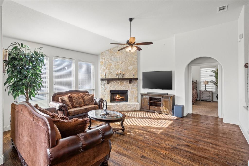 1814 Chadwick Lane Forney, TX 75126 - Photo 18 of 40 Living area with healthy amount of natural light, a stone fireplace, wood finished floors, a ceiling fan, and vaulted ceiling