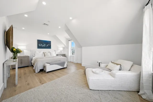 a spacious bedroom with a bed a couch and a potted plant