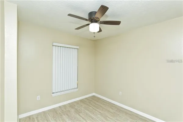 an empty room with wooden floor and a ceiling fan