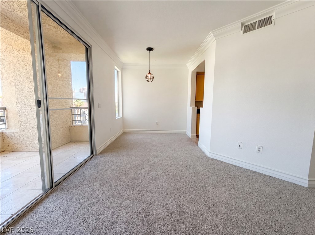 230 East Flamingo Road, Unit 320 Las Vegas, NV 89169 - Photo 9 of 19 A well-lit interior space with plush carpeting, crown molding, and a sliding glass door leading to a private balcony.