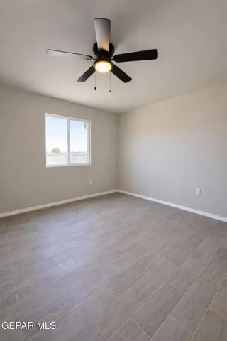 an empty room with a window and ceiling fan