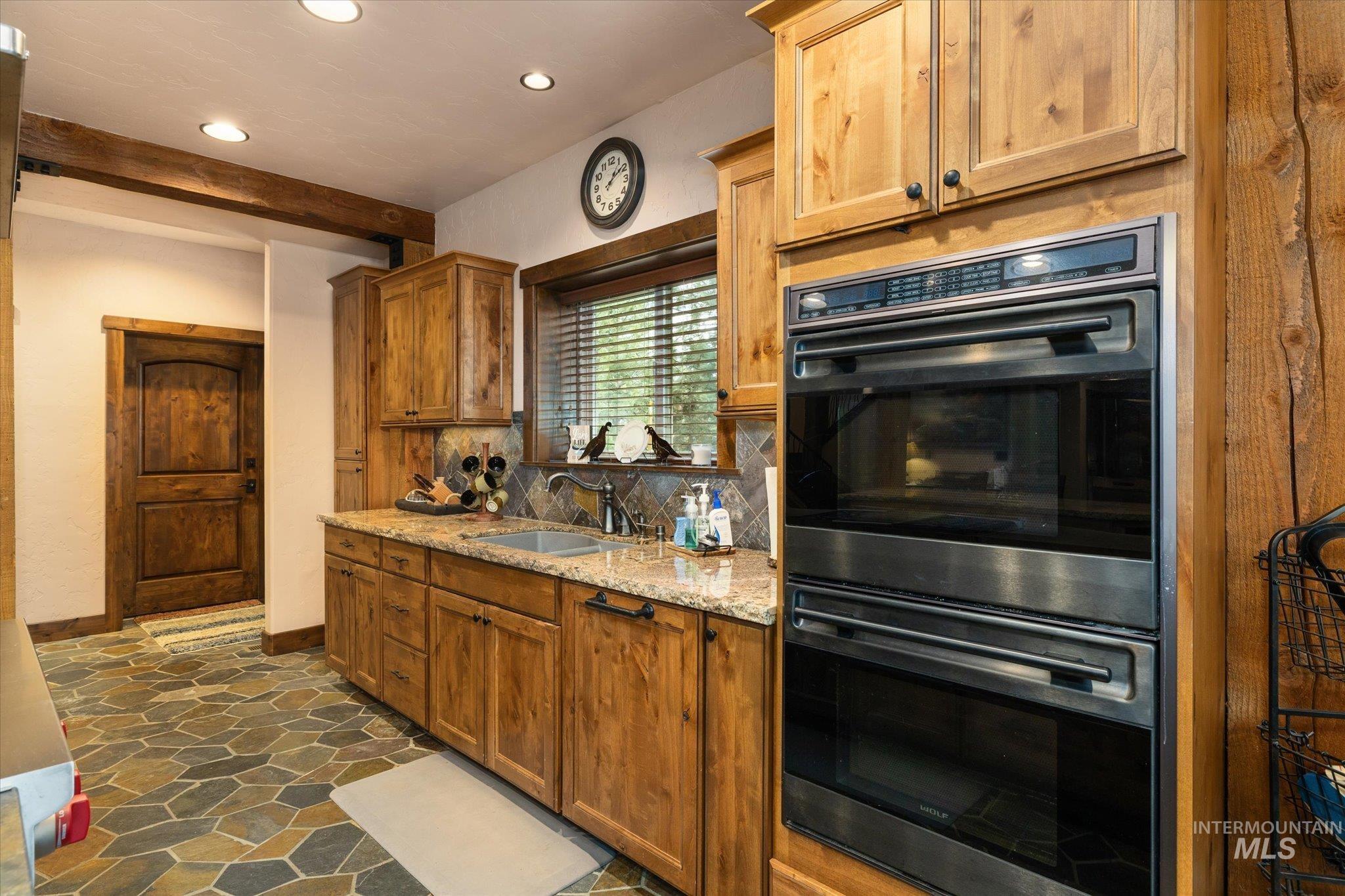 14 Pointe At Goldfork Court Donnelly, ID 83615 - Photo 14 of 49 Kitchen featuring stacked stainless steel ovens, wood cabinetry, granite countertops, and stone tile flooring