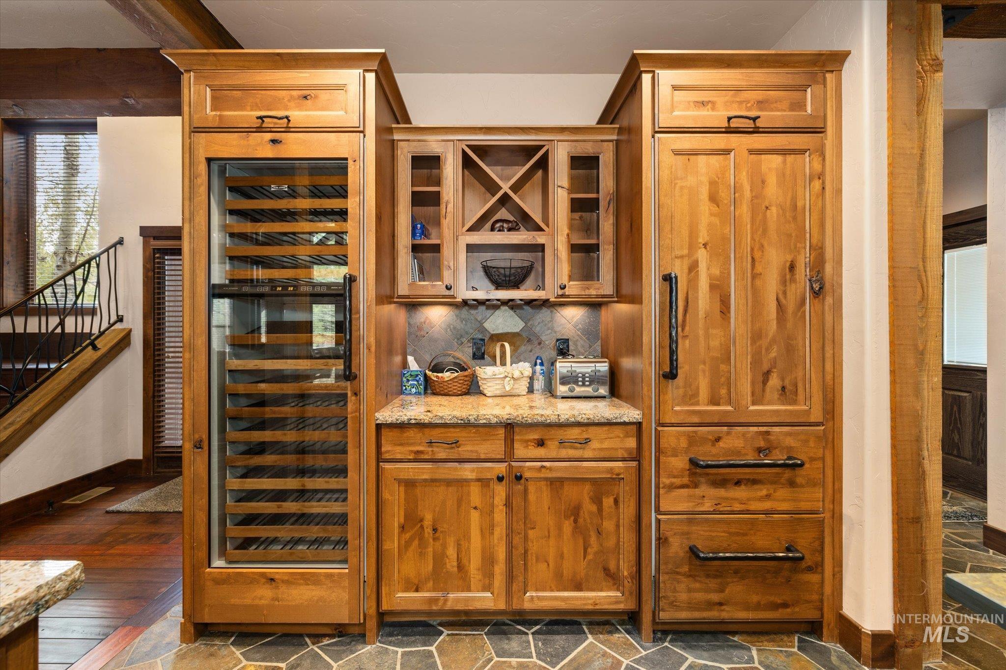 14 Pointe At Goldfork Court Donnelly, ID 83615 - Photo 15 of 49 Built-in beverage center featuring a glass-front wine refrigerator, custom wood cabinetry, granite countertops, and stone tile backsplash