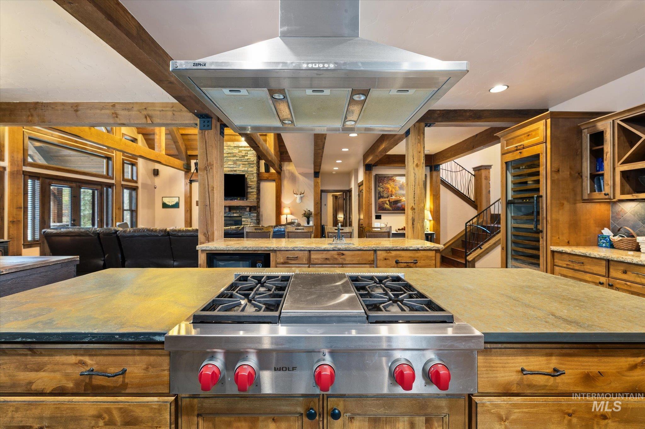 14 Pointe At Goldfork Court Donnelly, ID 83615 - Photo 16 of 49 Gourmet kitchen island featuring a stainless steel gas range with a matching professional-grade vent hood, wood-finish cabinetry, and stone countertops