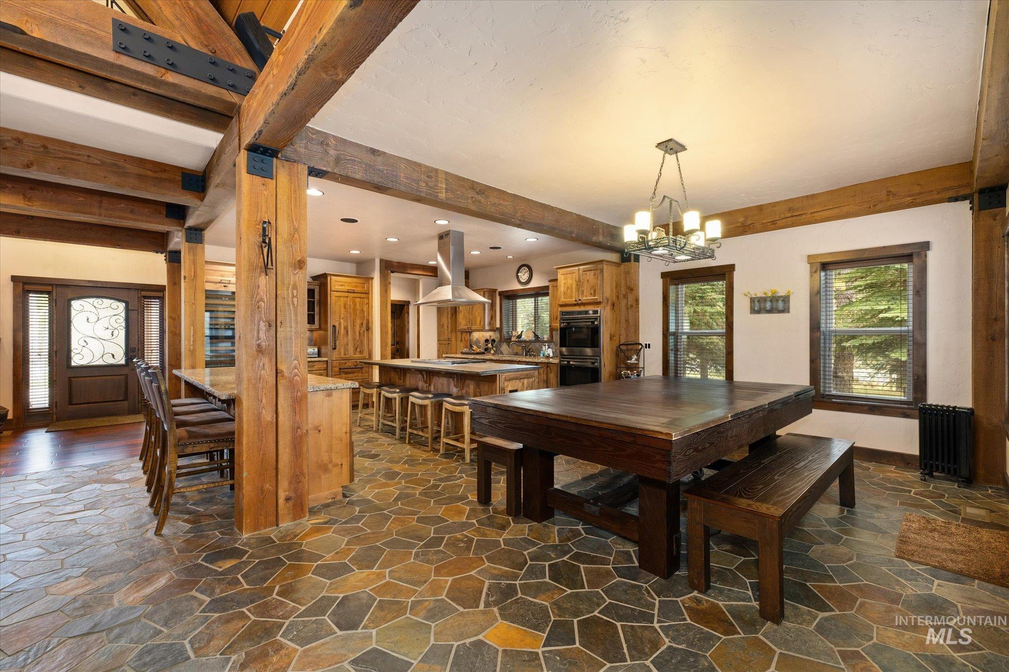 14 Pointe At Goldfork Court Donnelly, ID 83615 - Photo 17 of 49 Spacious interior featuring exposed wooden beams, flagstone flooring, a large kitchen island with seating, a built-in oven, and a double-door entryway with decorative glass
