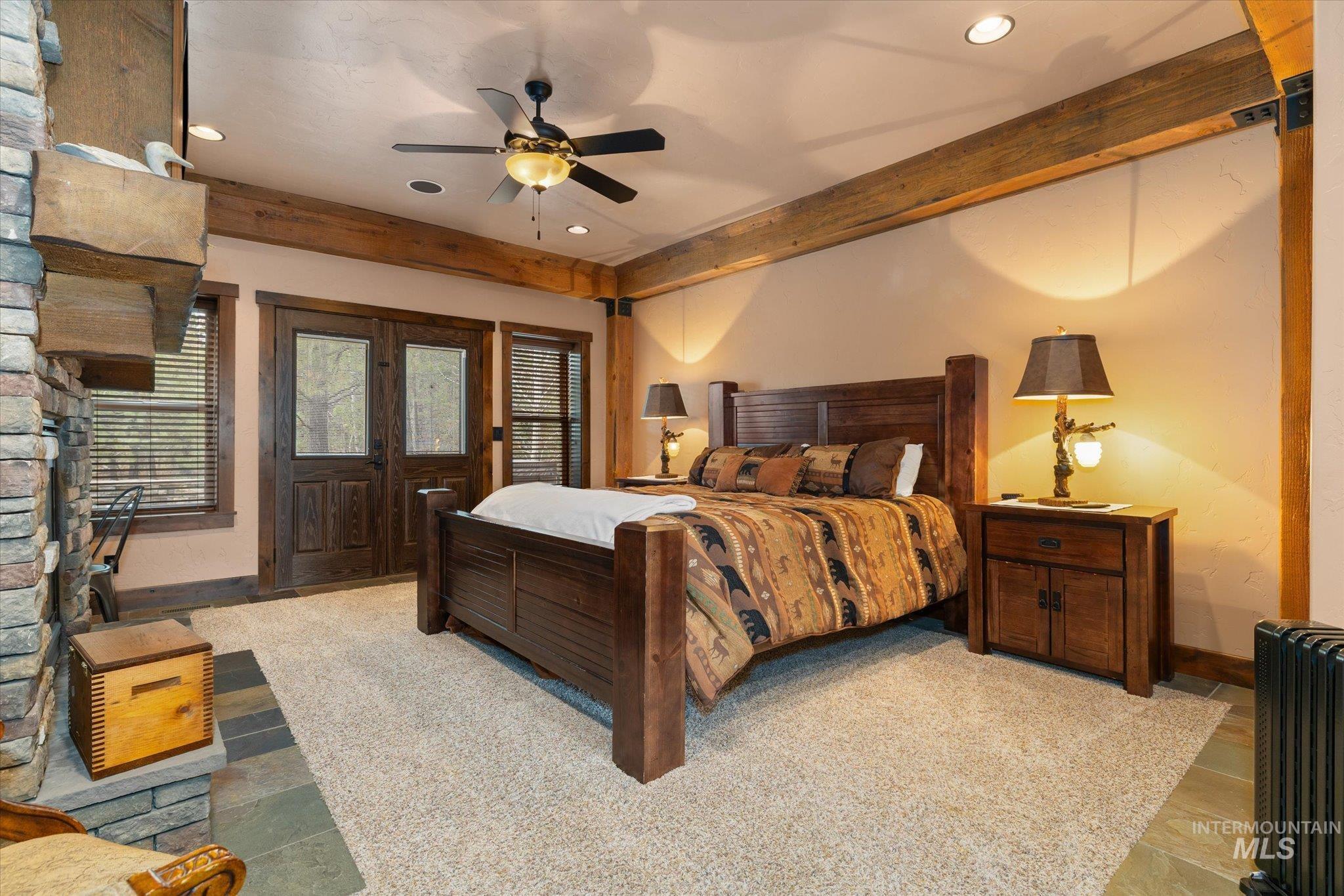 14 Pointe At Goldfork Court Donnelly, ID 83615 - Photo 20 of 49 Exposed wood beams accentuating the ceiling, a stone-faced fireplace with a substantial wood mantel, and double wood-frame doors with glass panels