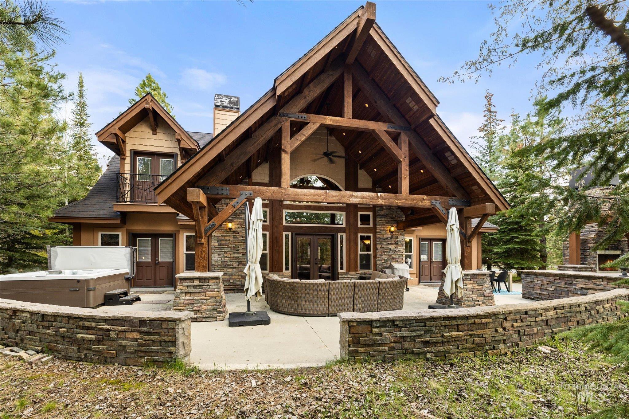 14 Pointe At Goldfork Court Donnelly, ID 83615 - Photo 2 of 49 Expansive rear patio featuring a prominent timber-frame porch, stone veneer accents, built-in hot tub, and stacked stone retaining walls