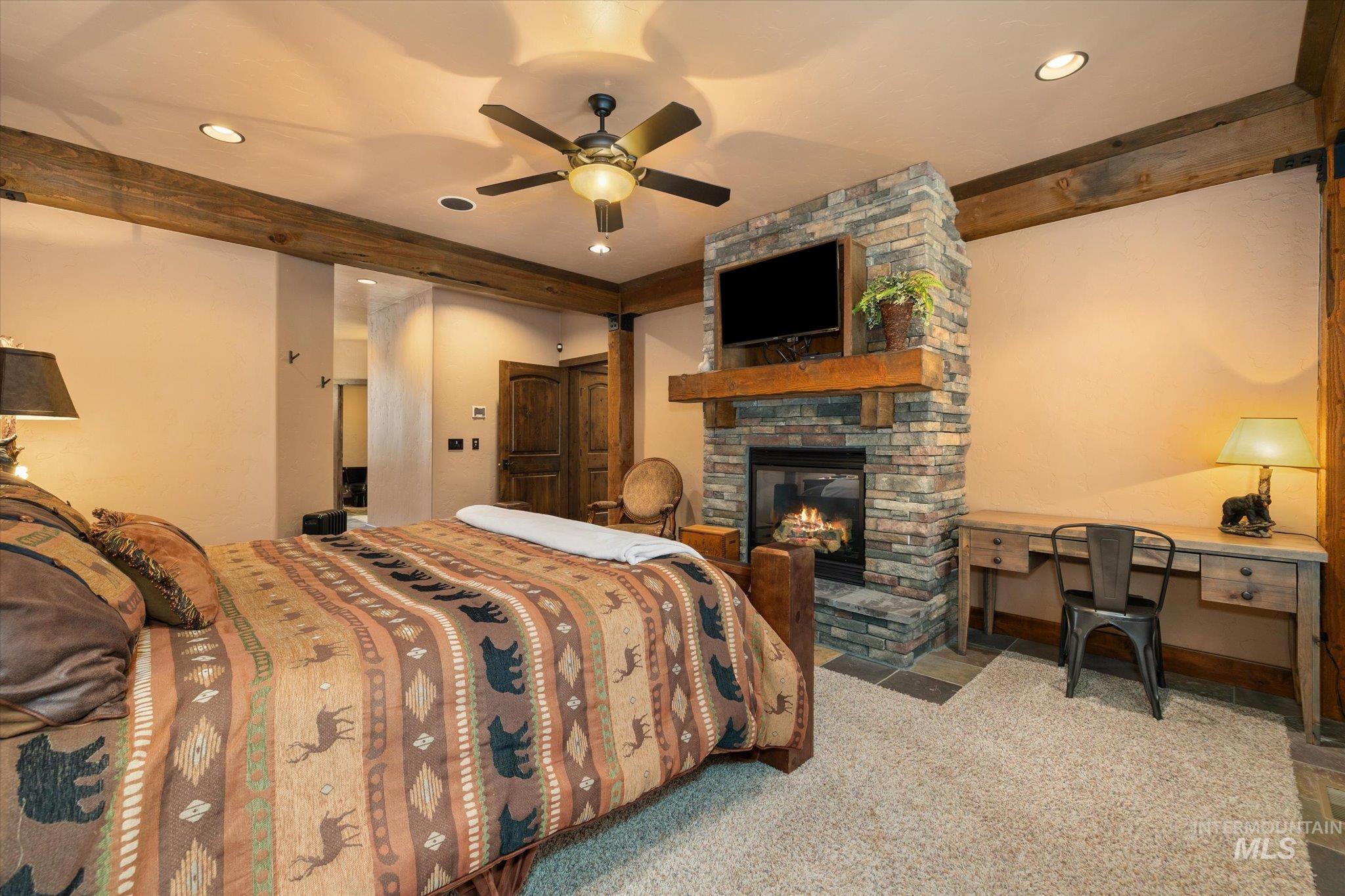 14 Pointe At Goldfork Court Donnelly, ID 83615 - Photo 22 of 49 Bedroom featuring a stone fireplace with a wood mantle, a built-in television mount, and exposed wood ceiling beams