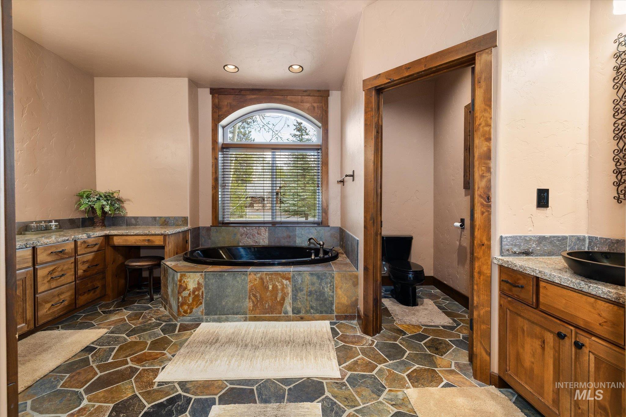 14 Pointe At Goldfork Court Donnelly, ID 83615 - Photo 23 of 49 Spacious bathroom featuring a built-in black soaking tub with a natural stone surround and an arched window