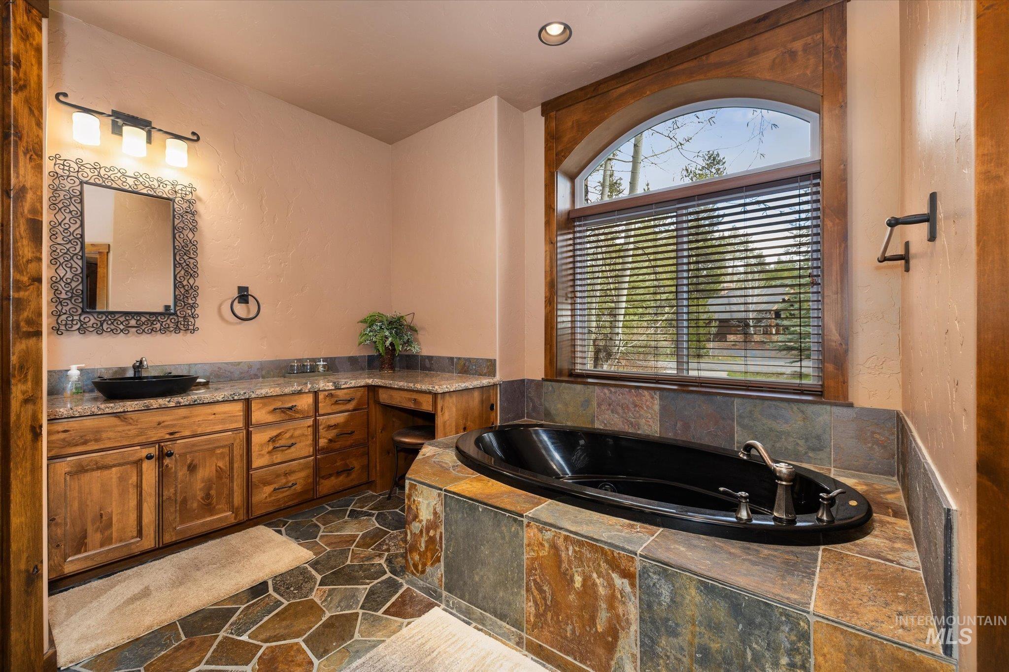 14 Pointe At Goldfork Court Donnelly, ID 83615 - Photo 24 of 49 Spacious bathroom featuring a built-in soaking tub, a large arched window with blinds, and a dual vanity with vessel sinks