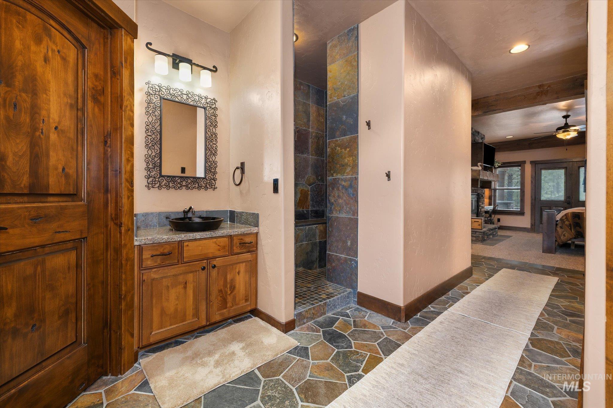 14 Pointe At Goldfork Court Donnelly, ID 83615 - Photo 25 of 49 Bathroom featuring a natural wood vanity with a vessel sink, a stone tile floor, and a stone-tiled shower enclosure