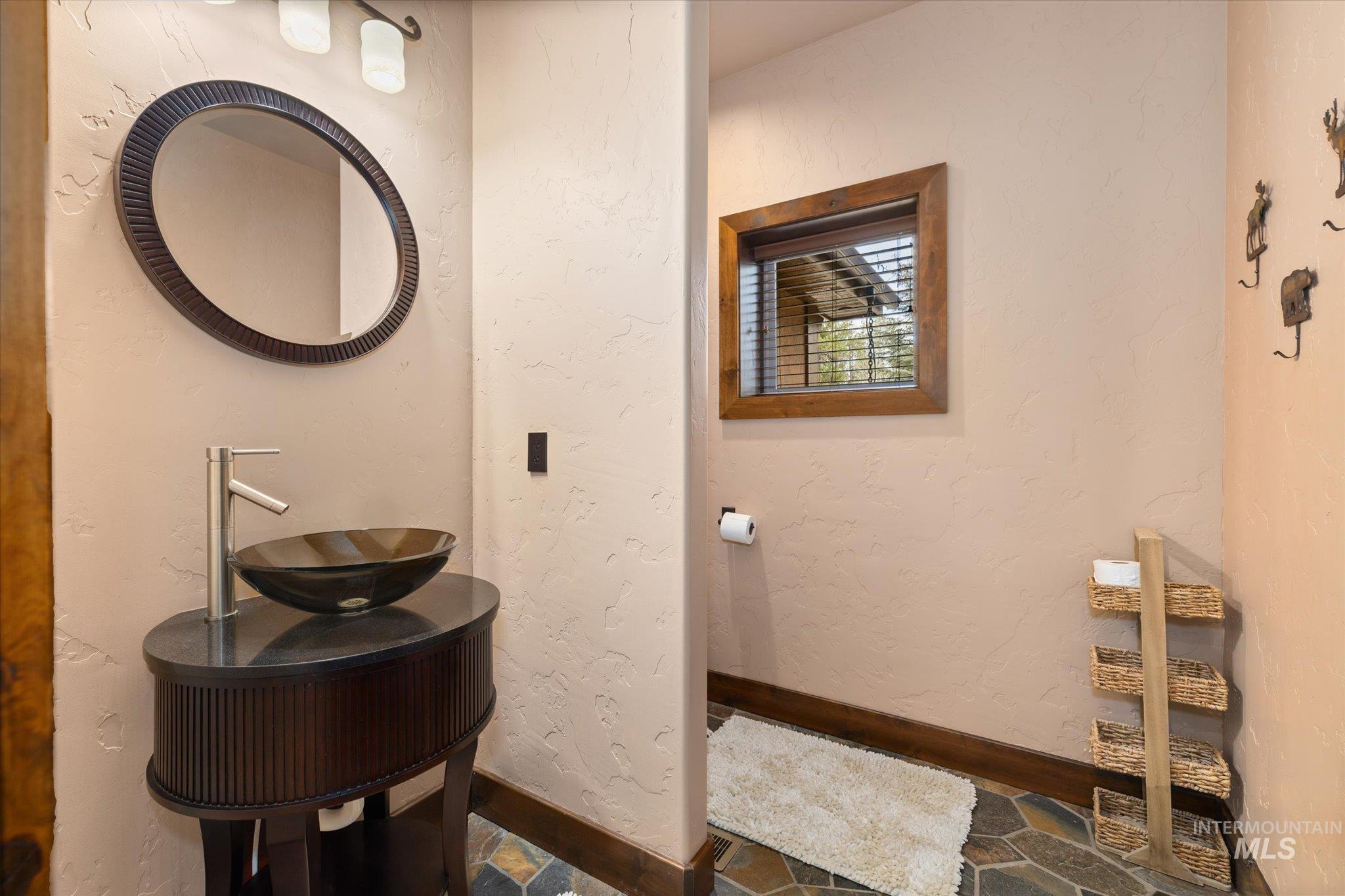 14 Pointe At Goldfork Court Donnelly, ID 83615 - Photo 29 of 49 Powder room featuring a vessel sink with a contemporary faucet, an oval mirror, and a wood-framed window