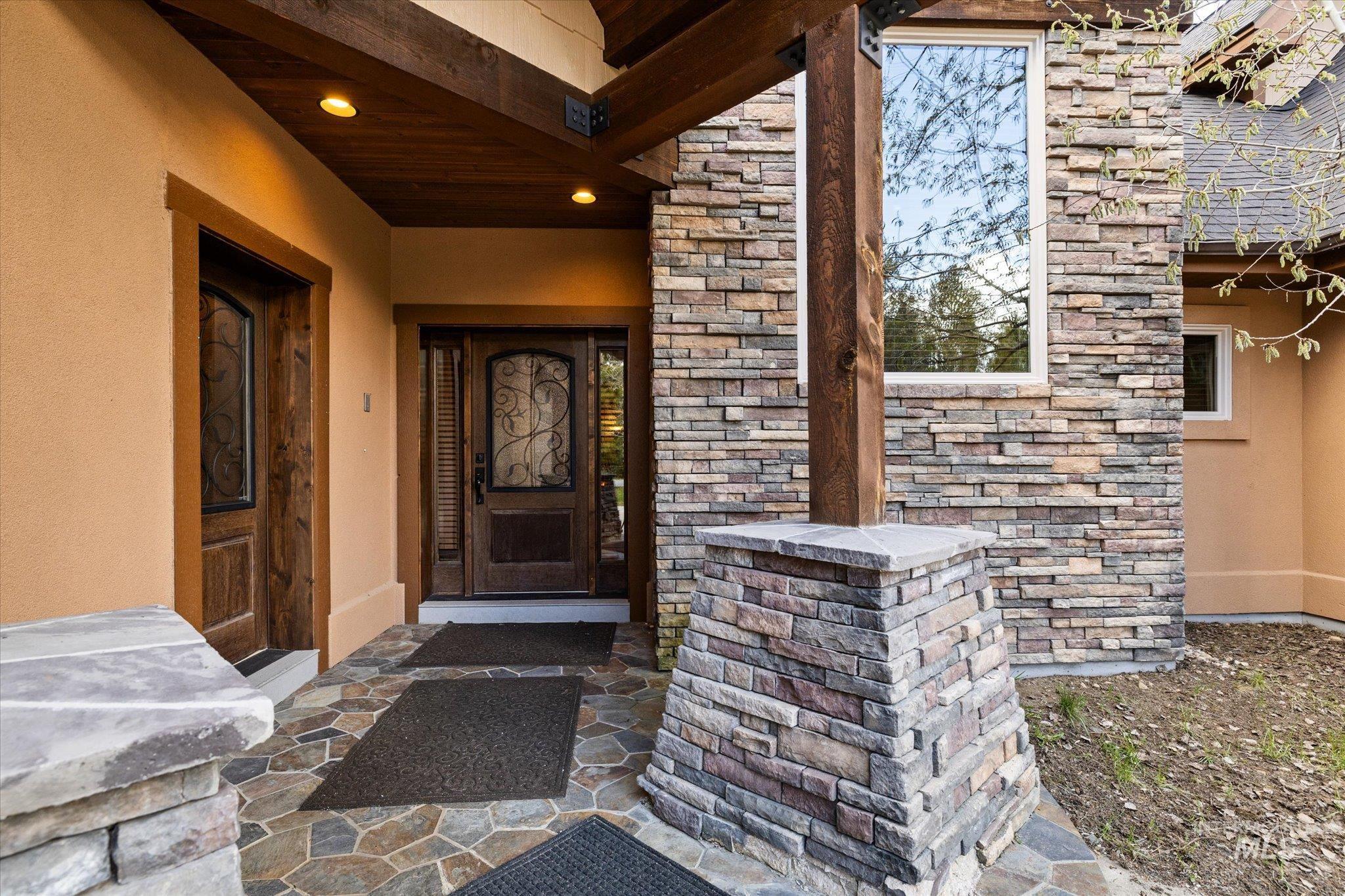 14 Pointe At Goldfork Court Donnelly, ID 83615 - Photo 43 of 49 Stone facade and stucco exterior featuring a wood-finish entry door with decorative ironwork, a second wood-finish door, and a flagstone patio