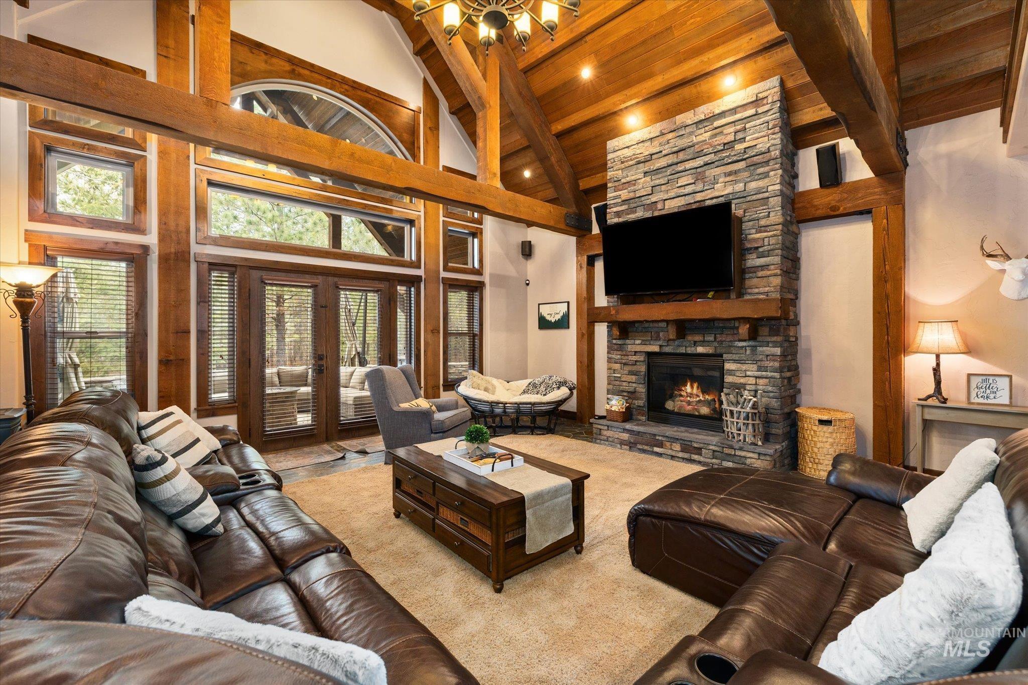 14 Pointe At Goldfork Court Donnelly, ID 83615 - Photo 5 of 49 Great room featuring a floor-to-ceiling stone fireplace, exposed wood beams, vaulted wood-paneled ceiling, large windows, and glass patio doors