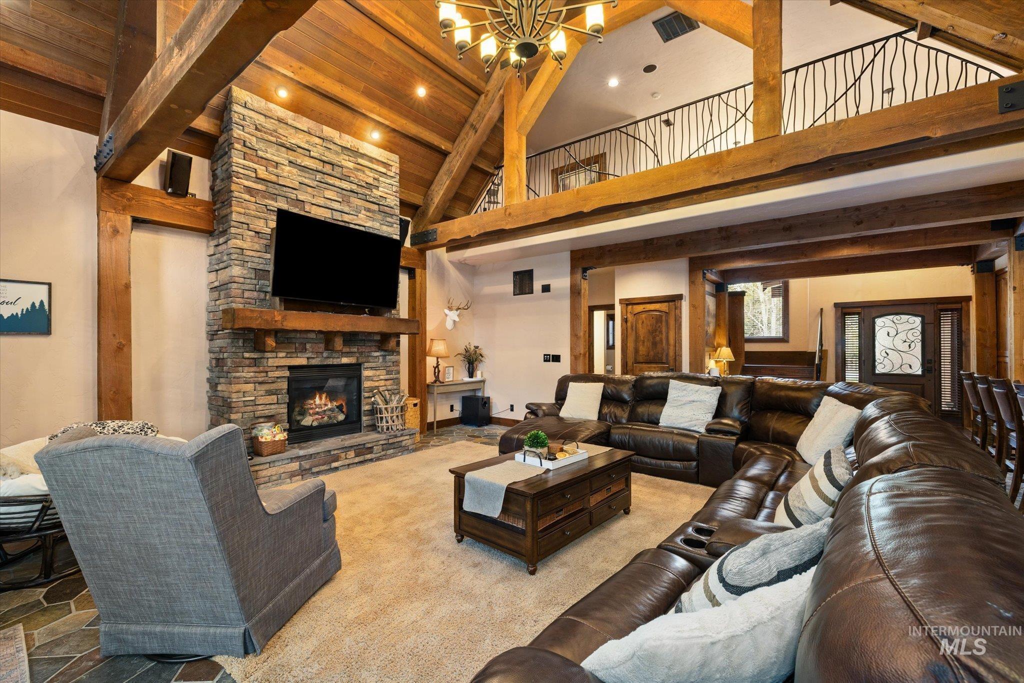 14 Pointe At Goldfork Court Donnelly, ID 83615 - Photo 7 of 49 Spacious living area featuring a stone fireplace with a wood mantle, vaulted wood-beamed ceilings, a decorative wrought iron balcony, and a multi-level layout