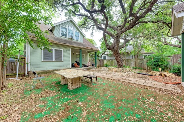 a backyard of a house with table and chairs and wooden fence
