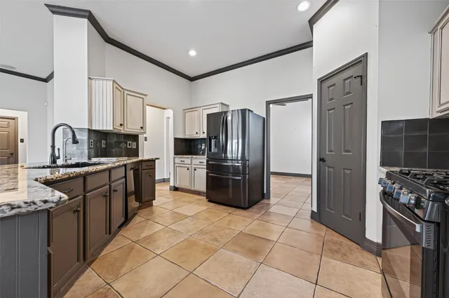 a kitchen with stainless steel appliances granite countertop a refrigerator a stove and a sink