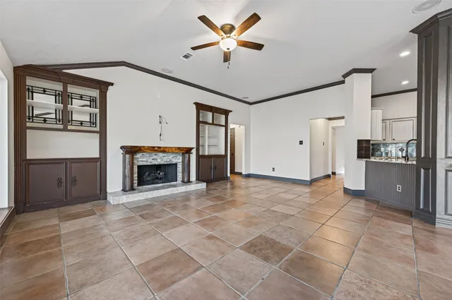 an empty room with wooden floor chandelier fan and windows