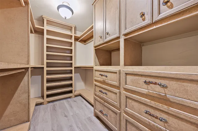 an empty room with wooden floor chandelier fan and windows