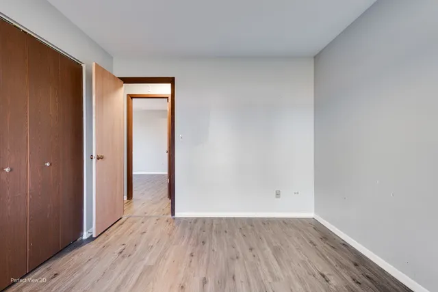 a view of an empty room with wooden floor and closet