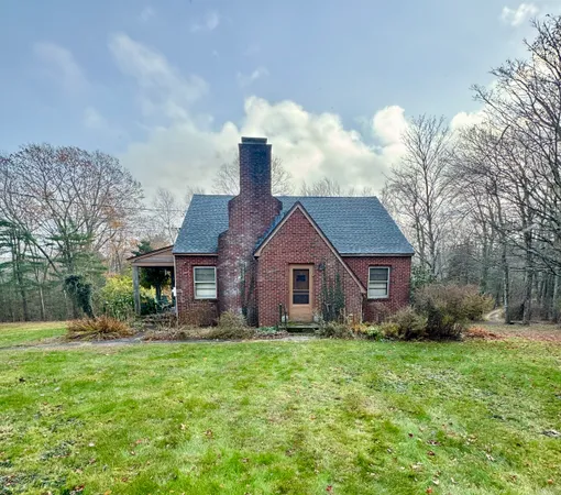 a view of a house with a yard and large trees