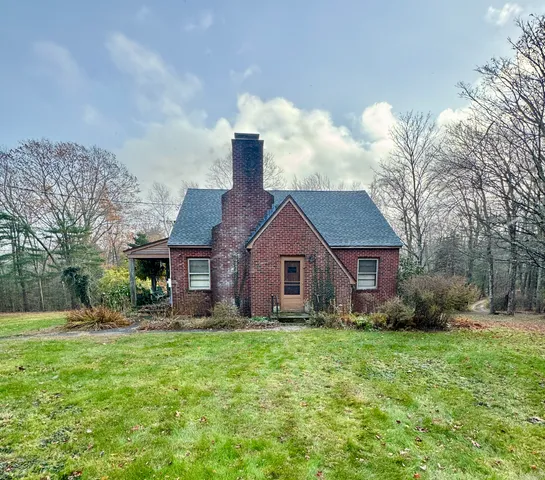 a view of a house with a yard and large trees