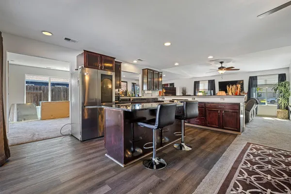 a kitchen with stainless steel appliances granite countertop a refrigerator a stove a sink dishwasher a dining table and chairs with wooden floor