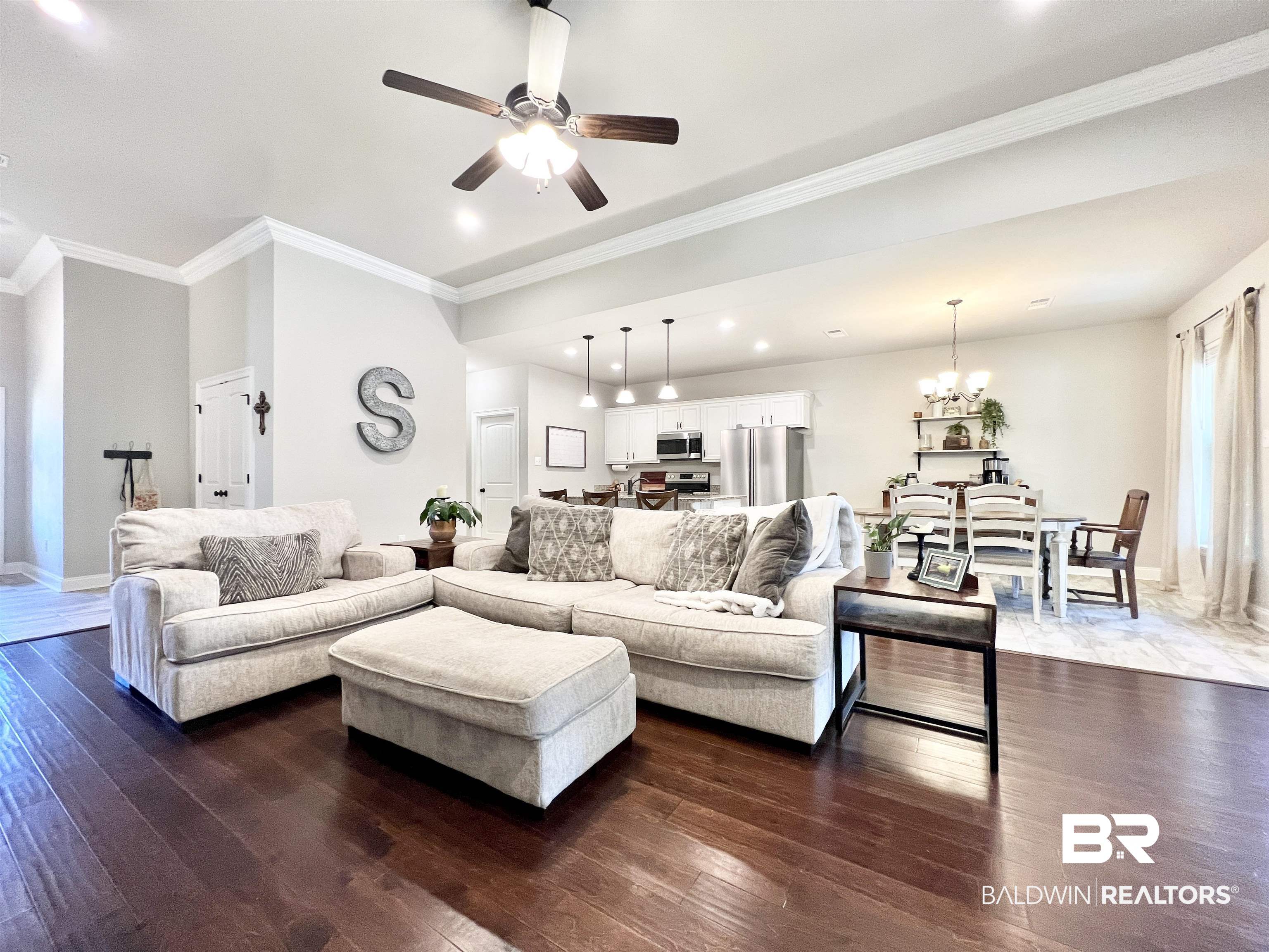32290 Calder Court Daphne, AL 36527 - Photo 18 of 59 Living room featuring dark wood-type flooring, crown molding, and ceiling fan with notable chandelier