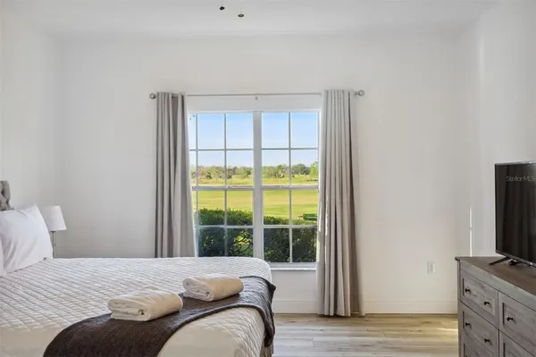 a bedroom with a bed and a flat tv screen next to a window