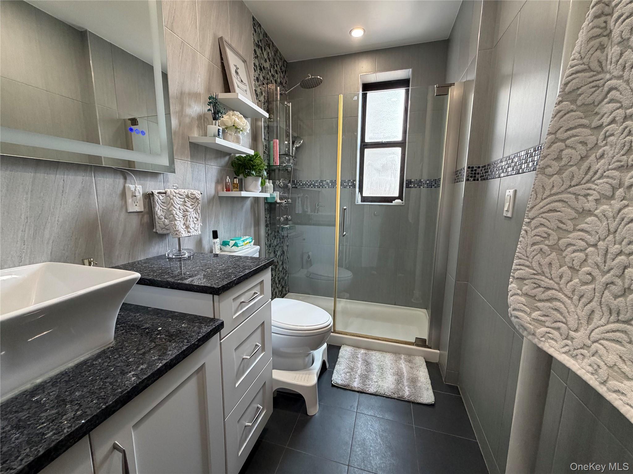 8384 116th Street, Unit 5G Queens, NY 11418 - Photo 13 of 17 a bathroom with a granite countertop sink a toilet and shower