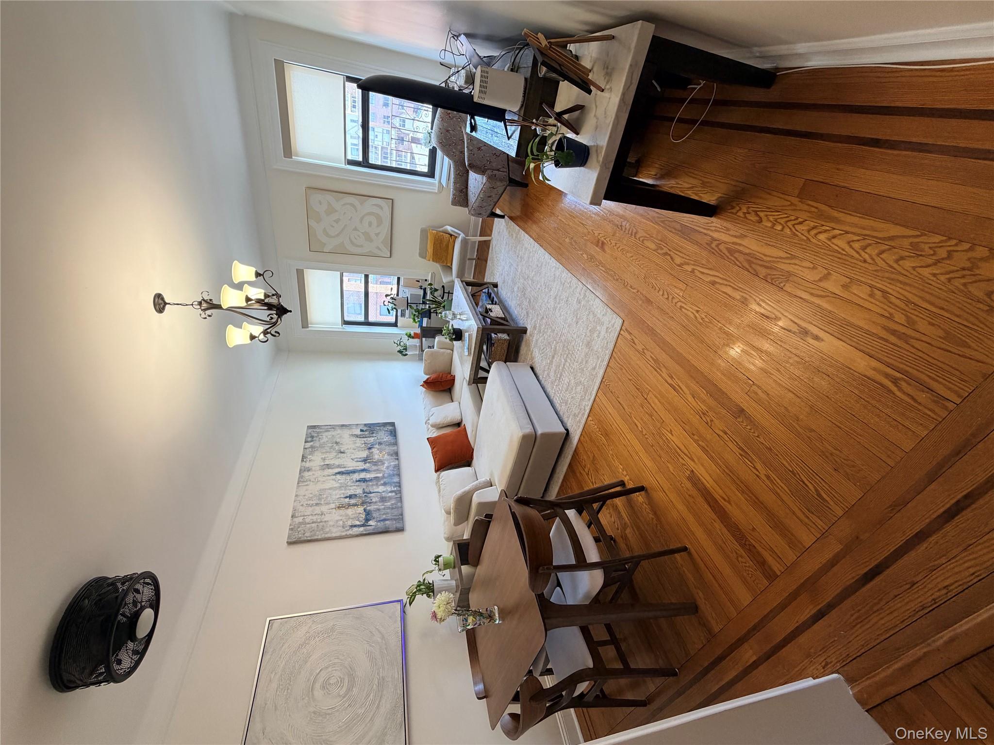 8384 116th Street, Unit 5G Queens, NY 11418 - Photo 14 of 17 a living room with furniture a chandelier and a table