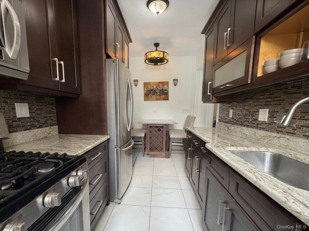 8384 116th Street, Unit 5G Queens, NY 11418 - Photo 4 of 17 a kitchen with stainless steel appliances granite countertop a sink and a stove