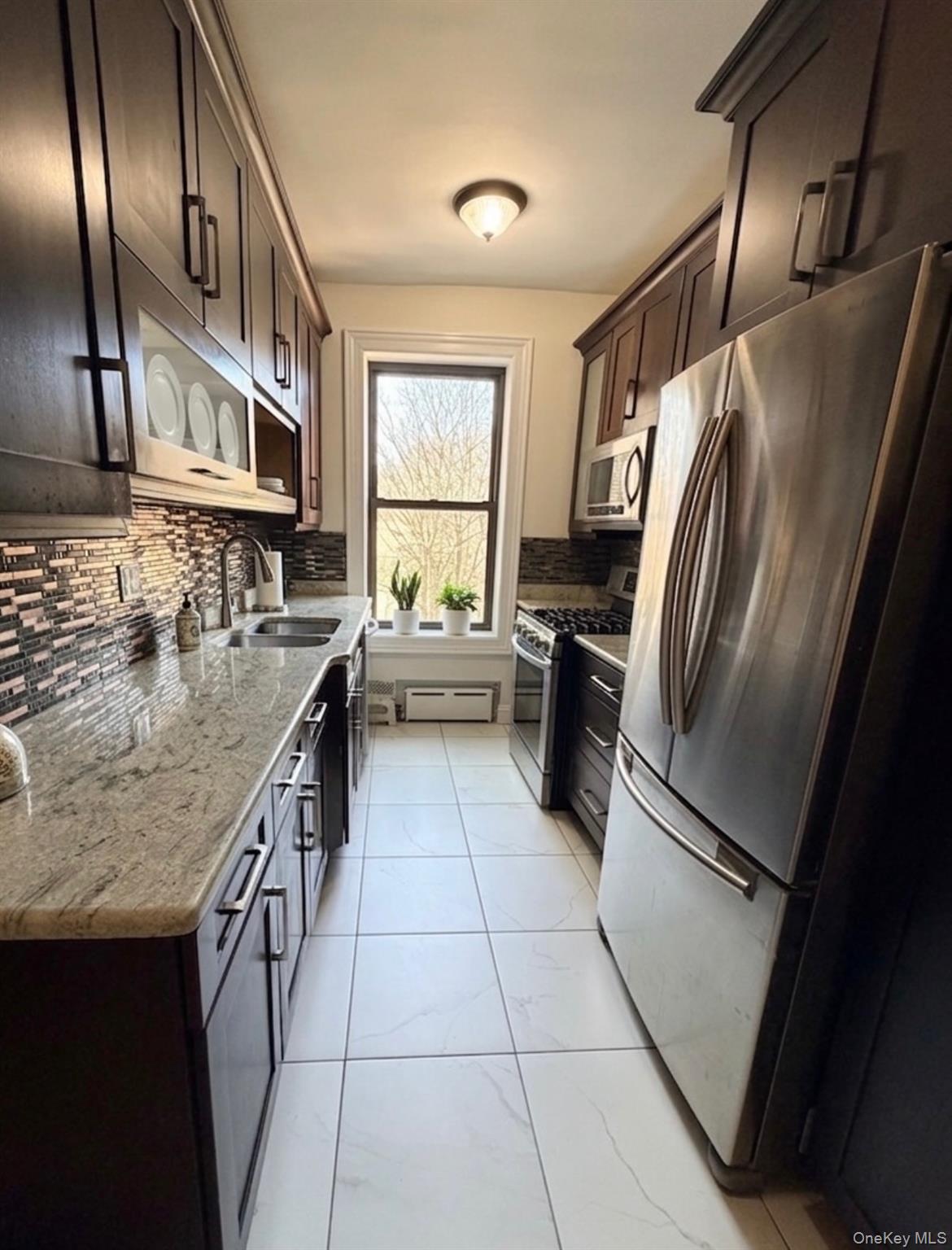 8384 116th Street, Unit 5G Queens, NY 11418 - Photo 5 of 17 a kitchen with granite countertop stainless steel appliances a sink stove top oven and cabinets