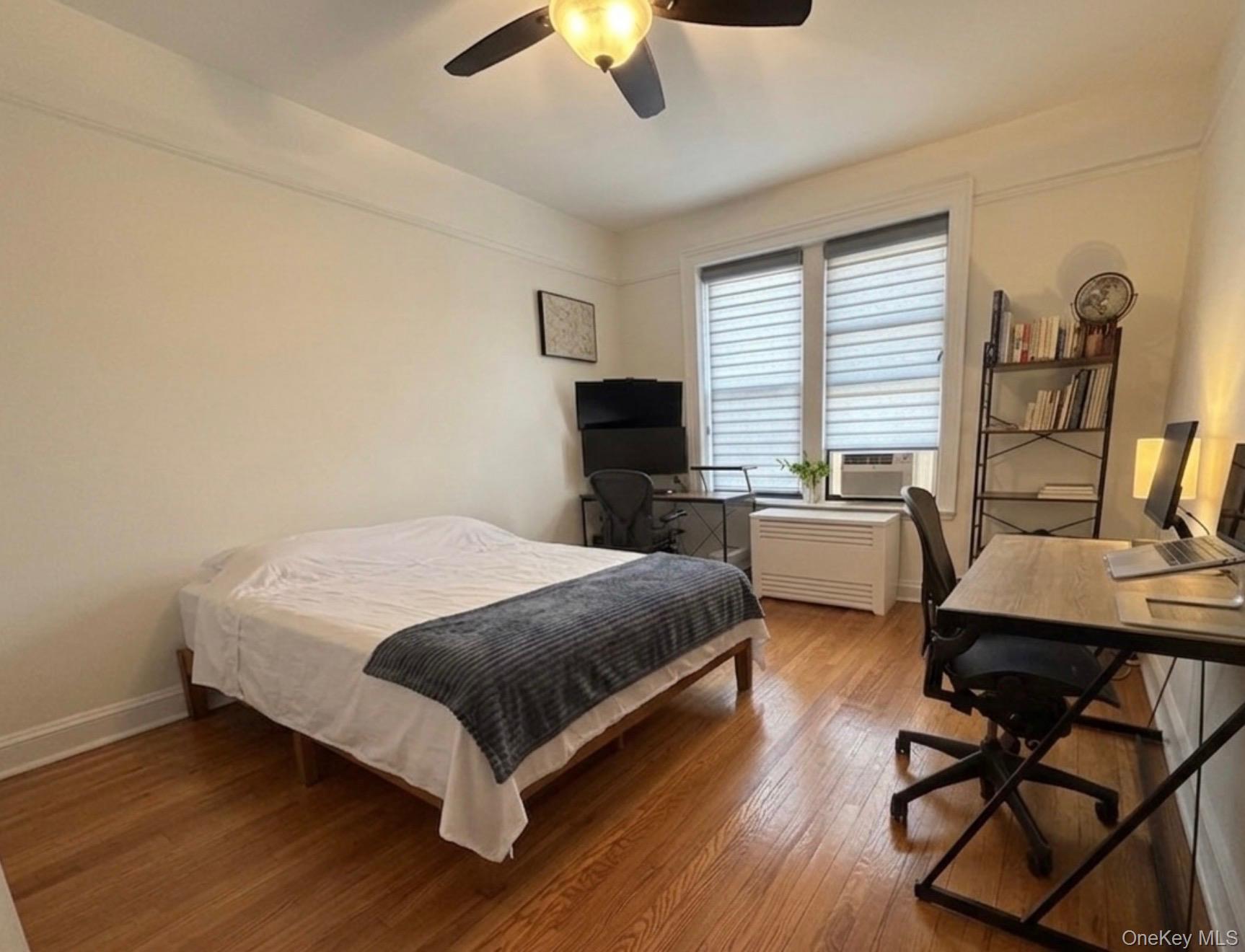8384 116th Street, Unit 5G Queens, NY 11418 - Photo 10 of 17 a bedroom with a bed a desk and chair with wooden floor