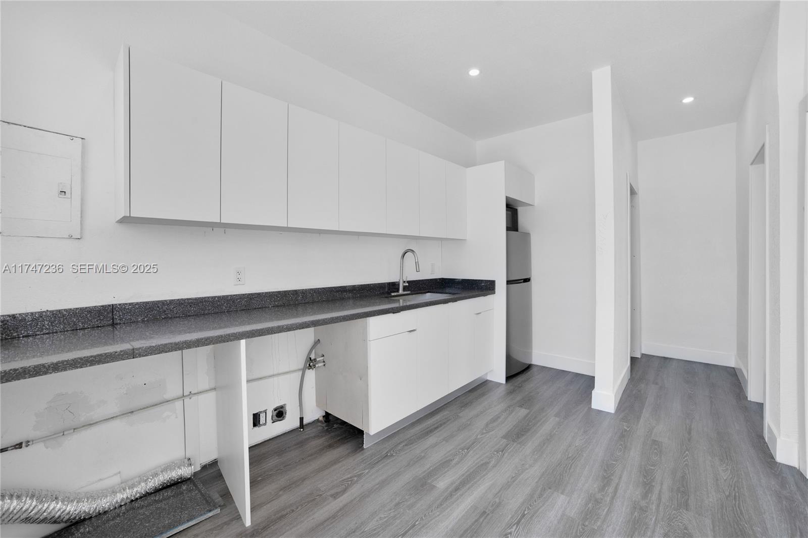 10272 Southwest 178th Street, Unit 1 Miami, FL 33157 - Photo 5 of 8 a kitchen with granite countertop white cabinets and a wooden floor