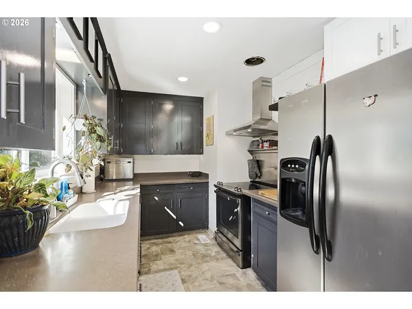 a kitchen with stainless steel appliances kitchen island granite countertop a refrigerator a sink a stove and wooden floor