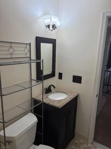 a bathroom with a granite countertop toilet sink and mirror
