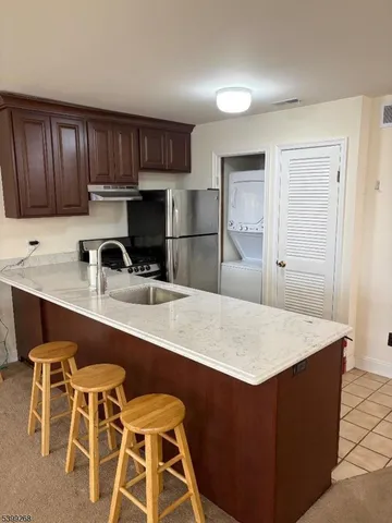 a kitchen with stainless steel appliances a sink a stove a refrigerator cabinets and a dining table