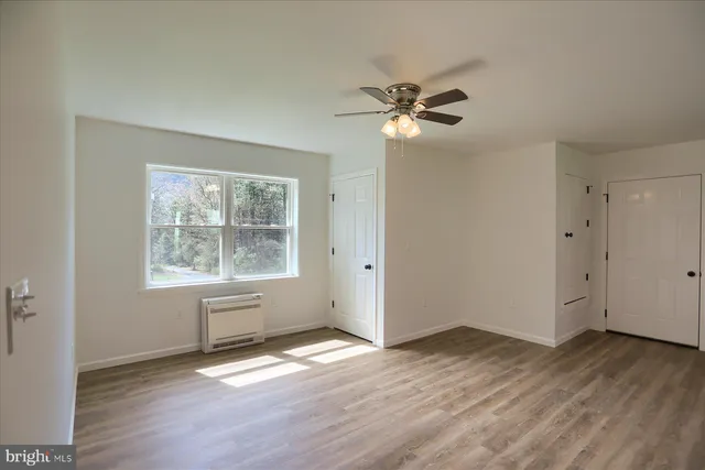 a view of empty room with wooden floor and fan