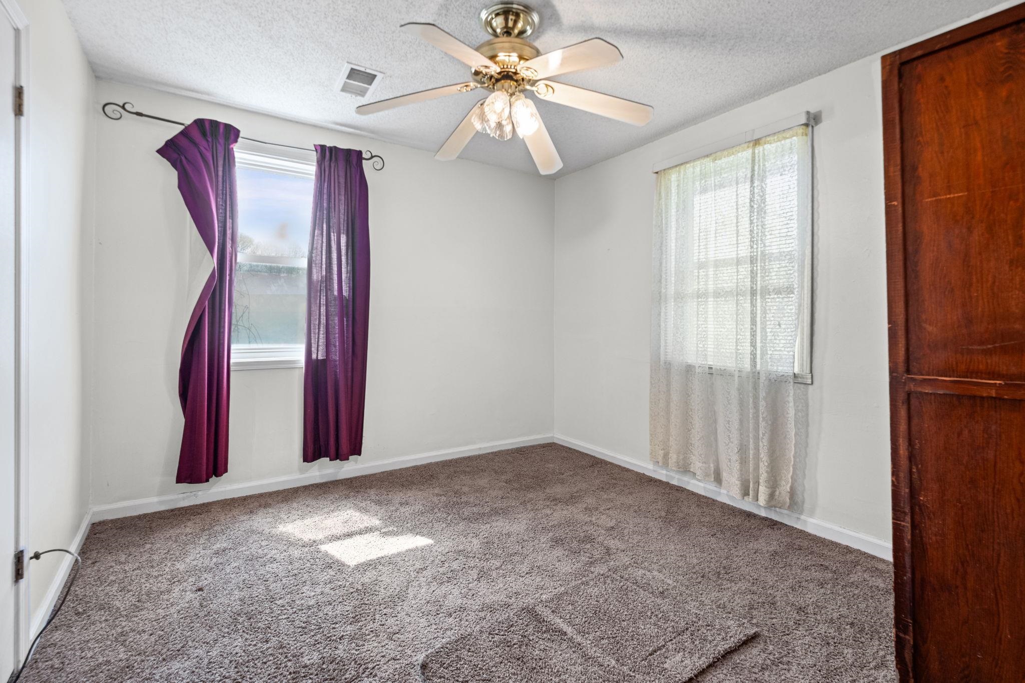 668 Westview Road Memphis, TN 38109 - Photo 13 of 27 Carpeted empty room featuring a ceiling fan, a textured ceiling, and healthy amount of natural light