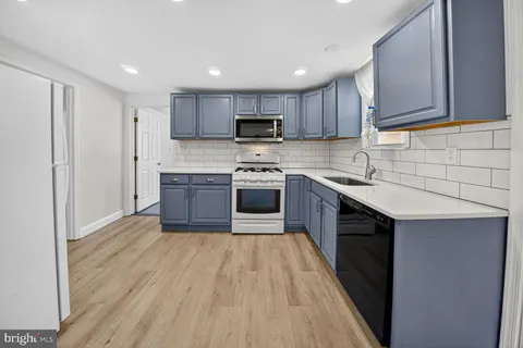 a kitchen with stainless steel appliances granite countertop a stove top oven a sink dishwasher and a refrigerator