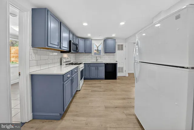 a large kitchen with stainless steel appliances granite countertop a refrigerator and a sink