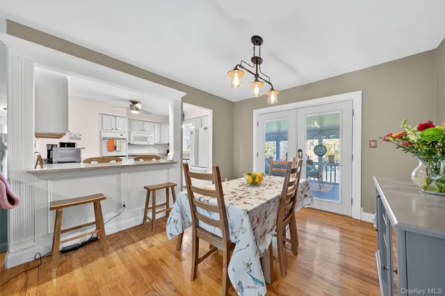 a dining room with wooden floor a chandelier a wooden table and chairs