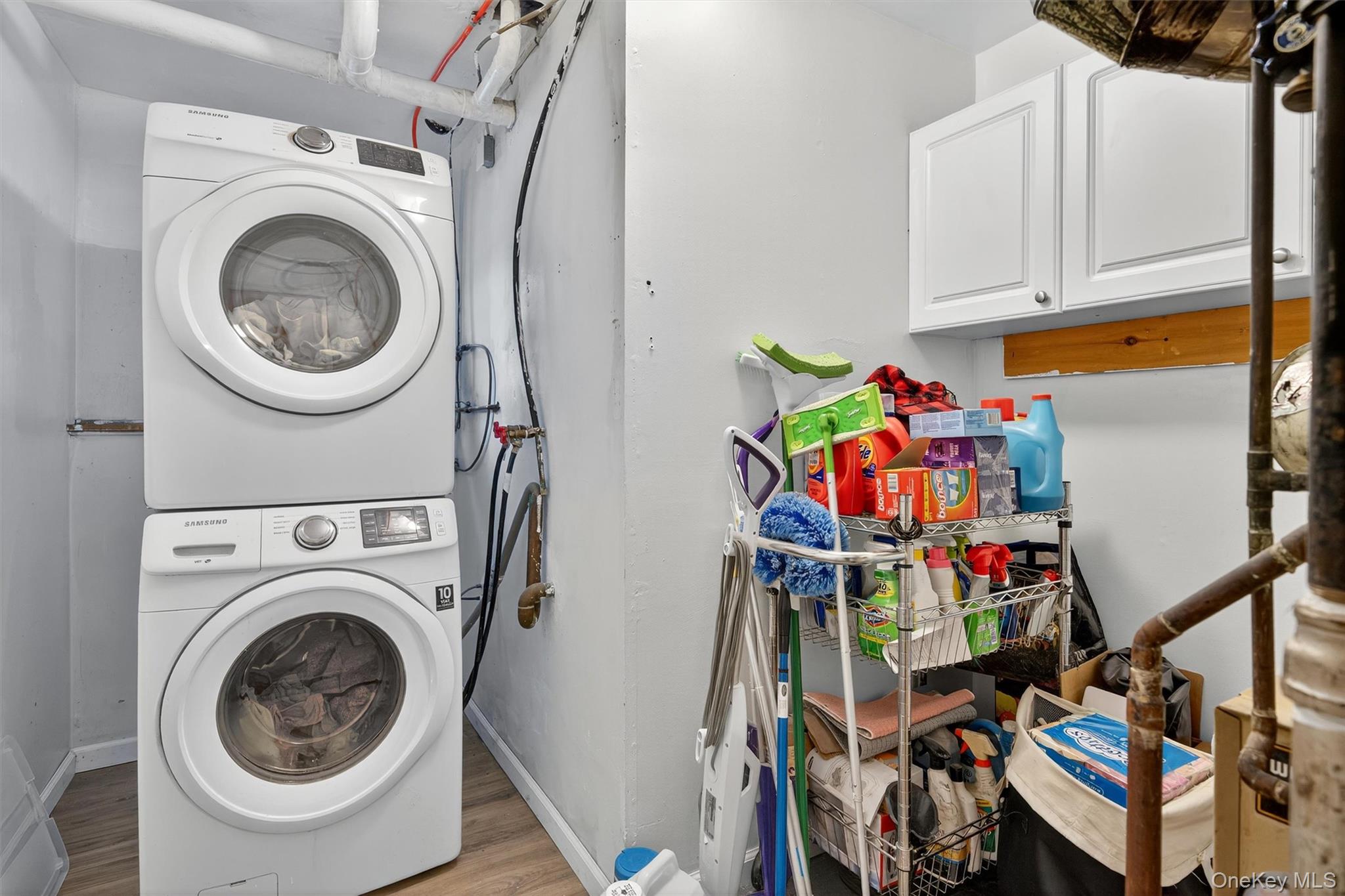 76 Pine Hill Road Highland Mills, NY 10930 - Photo 29 of 41 Laundry area featuring wood finished floors, stacked washer and clothes dryer, and cabinet space