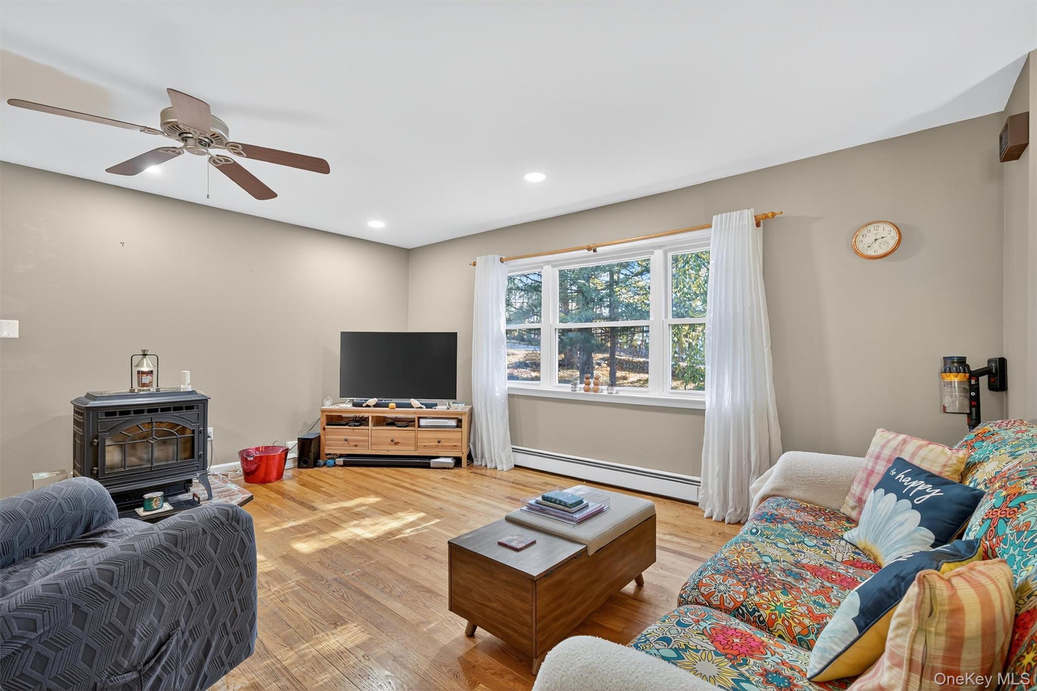 76 Pine Hill Road Highland Mills, NY 10930 - Photo 9 of 41 Living room featuring wood finished floors, a wood stove, a baseboard heating unit, recessed lighting, and ceiling fan