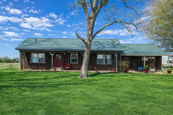 a view of a brick house with a big yard and large trees