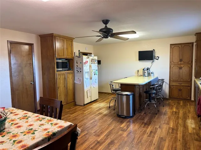 a kitchen with stainless steel appliances kitchen island granite countertop a refrigerator a stove top oven a dining table and chairs with wooden floor